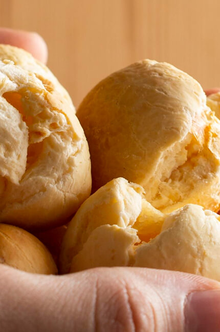 Pessoa segurando vários pães de queijo