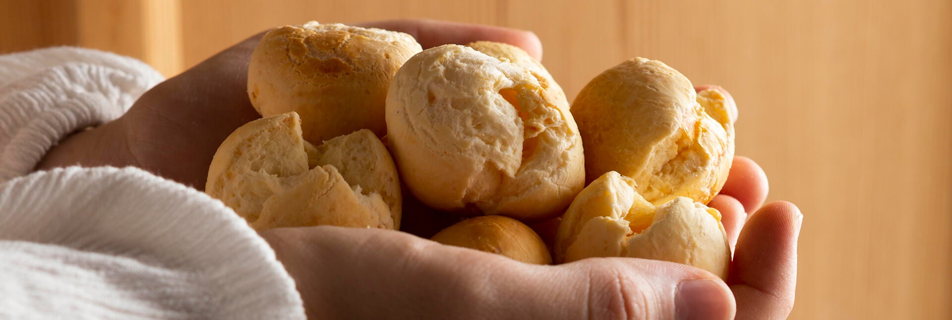 Uma pessoa segurando pães de queijo nas mãos